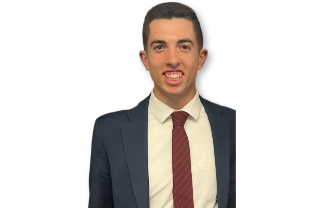 Sai Brazier in a navy suit and burgundy striped tie.